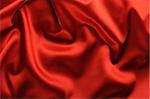 red satin background. A satiny fabric with beautiful light-shadow waves