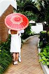 Bride and groom with a bright red parasol.