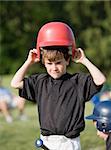 Little Boy Putting on Helmet Getting Ready to Hit