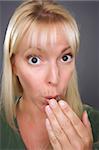 Shocked Blond Woman with Hand in Front of Mouth Against a Grey Background