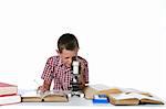 cute young boy looking through a microscope and taking notes