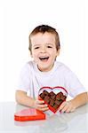 Happy boy with chocolate in red heart shaped box - isolated