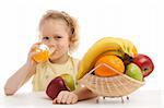 Child sitting near fruit vase and drinking juice