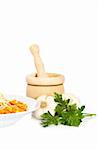 Plate of pasta, parsley, garlics and wooden mortar reflected on white background. Shallow depth of field