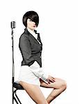Young woman with fashion haircut sitting back to the vintage microphone, on white
