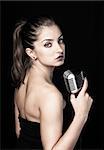 Beautiful woman holding retro microphone on black background