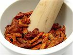 Pestling dried red hot chili pepper in a bowl of chinaware