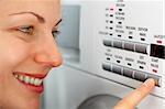 smiling female pressing a button on her washing machine