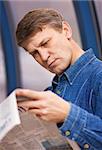 Serious middle aged man reading newspaper