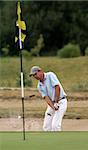 A professional golfer playing a shot out of a sand-trap with excellent control.