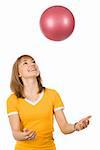 A girl throwing a red ball up