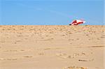 Sand beach close-up with colorful parasol on background over the blue skies