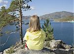 Small girl sits it on the shore and looks at sea