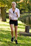 cute young girl running and listening music in park near river almost in sunset