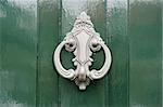 Detail of a shiny green door with a silver-colored door knocker