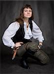 Girl - pirate with pistol sit on black background