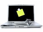 Damaged laptop with a spanner over it and a blank post-it on the screen. Isolated on white.