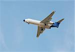 White passenger airplane landing against clear blue sky