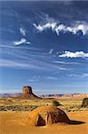 Hogan - the traditional Navajo red clay earth house, with backdrop of famous table mountains of the Navajo National monument on the background