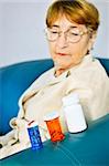 Elderly woman looking at pill bottles with medication