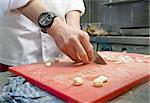 A chef cutting garlic in a professional kitchen