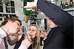 three young, drunken adults taking the last drop of champagne at a bar