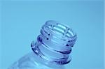 Neck of an open plastic water bottle on blue background