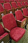 red theatre seats with white numbers, one seat unfolded