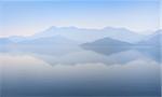 Mountain peaks covered with blue mist and still waterscape on the background in Montenegro.