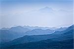 Mountain peaks covered with dark woods in blue mist. Montenegro.