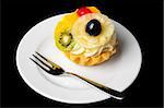 small fancy fruit cake on plate, isolated on black