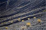 Fragment of black lava and ornage clay and salt mineral deposits in geological formations in Ubehebe Volcano, Death Valley National Park