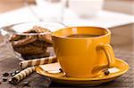 Still life with yellow cup of coffee and pastry