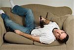 A drunk man is passed out on the couch from drinking too much beer
