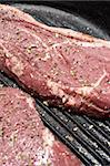 Raw steaks being prepared in a black cast iron skillet