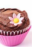 Miniature chocolate cupcake with icing and pink flower on white background. Macro shot. Shallow depth of field