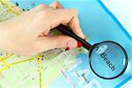 Closeup of woman?s hand holding a magnifying glass on the map. Concept of beach tourism