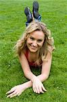 Blonde girl lying on green grass in a park