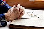 An old pair of hands in prayer on a book