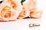 Wedding rings and roses in background