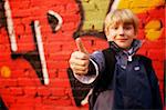 Cool kid standing in front of a graffiti wall. Focus in hand