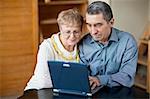 Old couple sitting together and using laptop