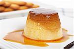 Vanilla cream caramel dessert and cookies on white dish. Shallow depth of field