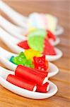 Assortment of candies in the spoons with soft shadow in the wooden background. Shallow depth of field