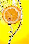 View of sliced orange getting splashed  on yellow  back