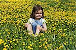 Crying girl sitting on a meadow full of buttercup