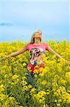 happy blond girl with open arms enjoying in a yellow field