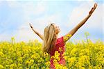 happy blond girl with open arms in a big hug to the sky in a yellow field