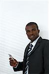 young adult businessman holding mobile phone. Shadows from venetian blinds on wall. Copy space