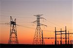 Silhouetted power pylons against a red sky at sunset